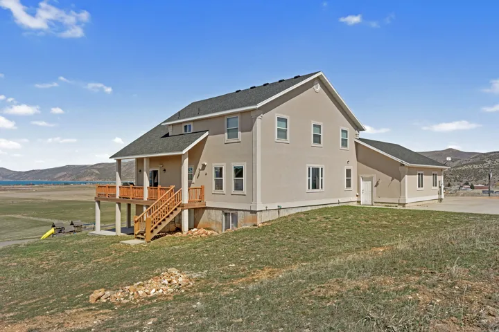 Stucco exterior residence featuring a covered wood-deck balcony with stairs and a lower-level walkout