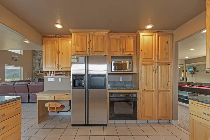 Kitchen featuring natural wood cabinetry, stainless steel appliances, granite countertops, and tile flooring