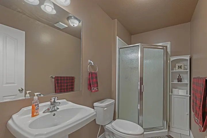 Bathroom featuring a white pedestal sink, chrome faucet, and a large wall mirror