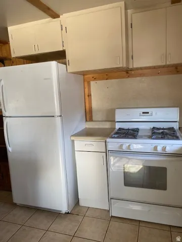Kitchen with white appliances, white cabinets, light countertops, and light tile patterned floors