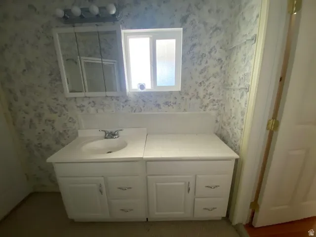 Bathroom featuring wallpapered walls and vanity