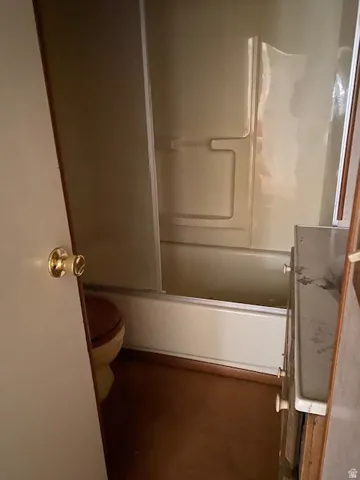 Full bathroom featuring toilet and combined bath / shower with glass door