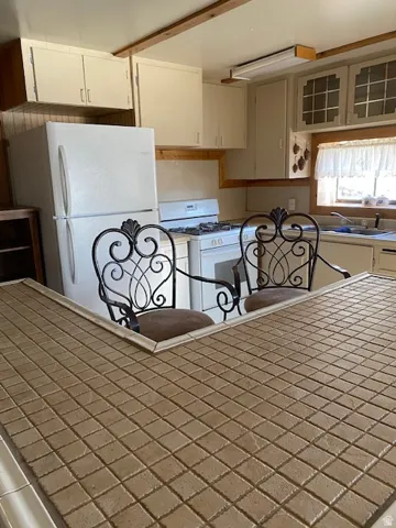Kitchen with white appliances, glass insert cabinets, and white cabinets