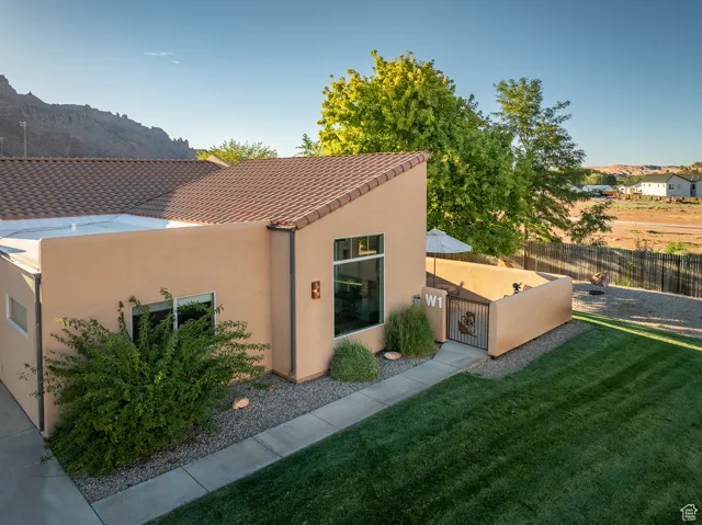 Exterior space with a lawn, stucco siding, and fence