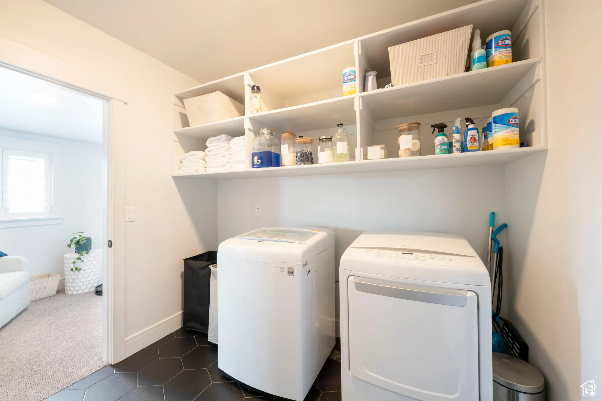 Laundry area with independent washer and dryer, dark tile patterned floors, baseboards, laundry area, and dark colored carpet