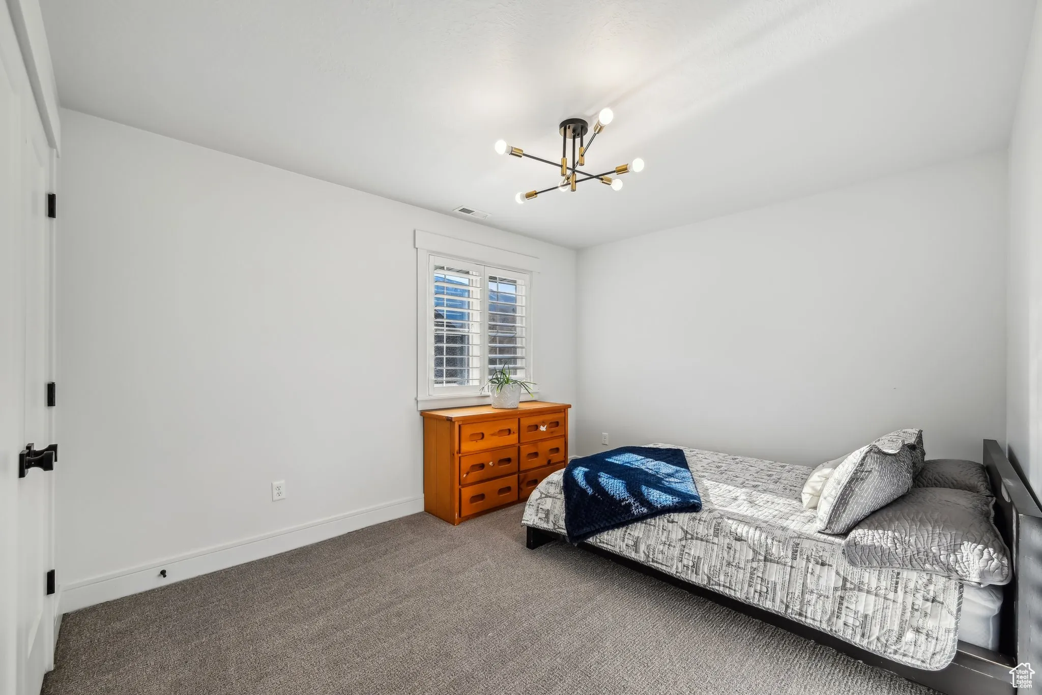 Carpeted bedroom with visible vents, baseboards, and a notable chandelier