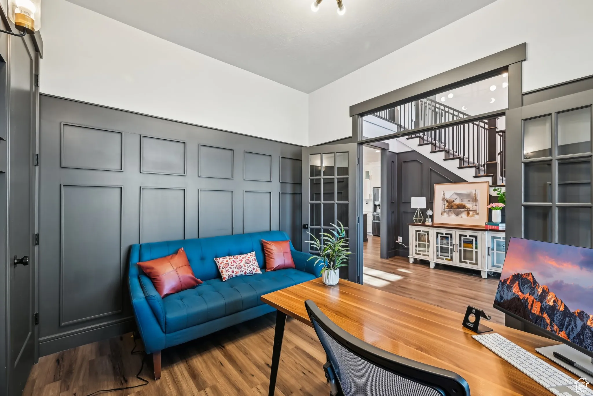 Living area featuring stairs, a towering ceiling, a decorative wall, and wood finished floors