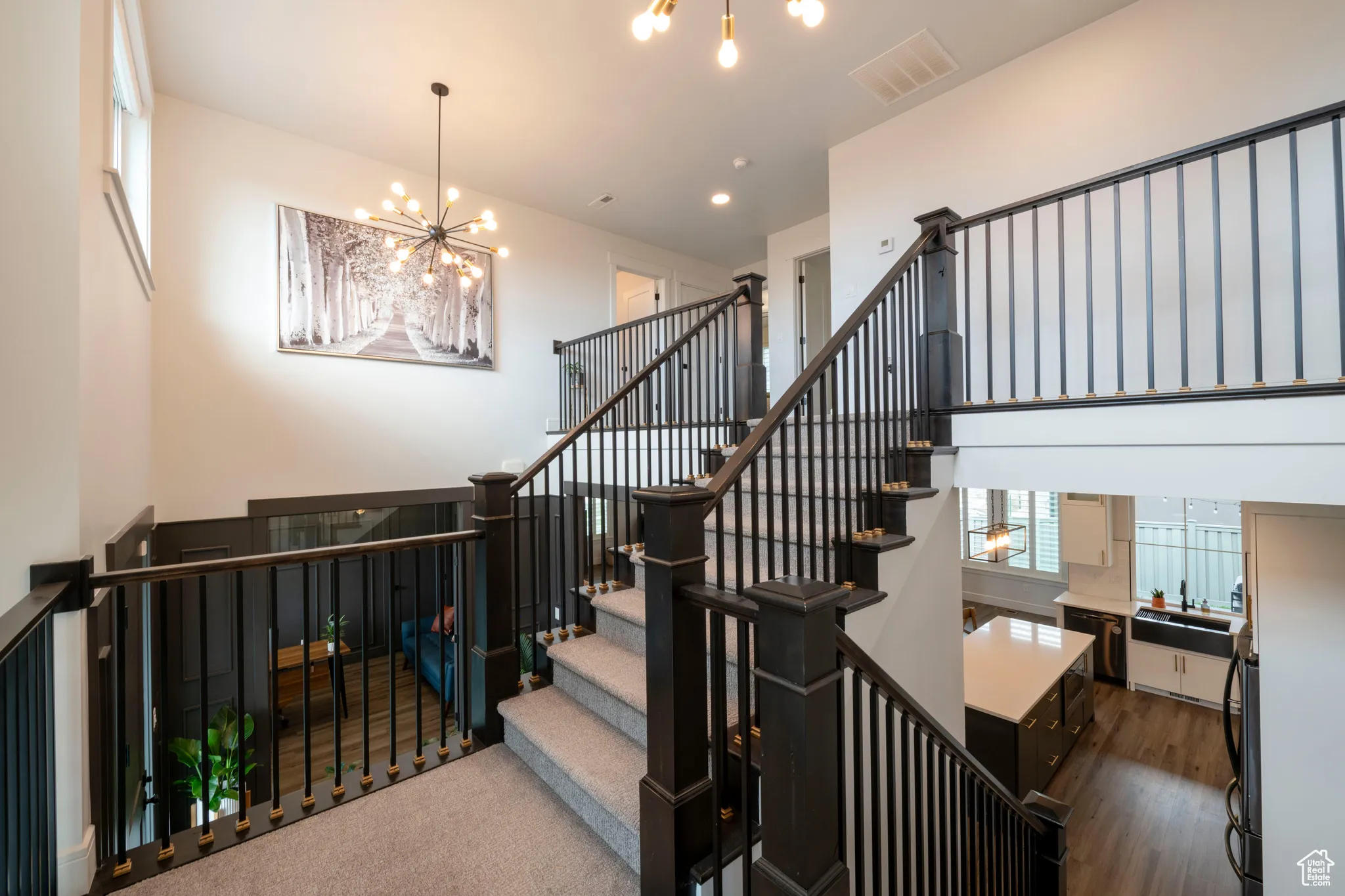 Staircase with visible vents, wood finished floors, and a notable chandelier