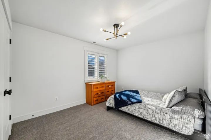 Carpeted bedroom with visible vents, baseboards, and a notable chandelier