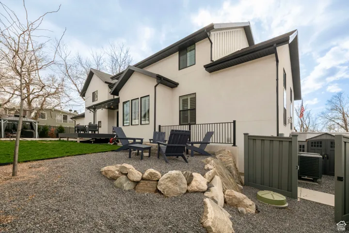 Rear view of property featuring an outdoor structure, stucco siding, a patio, central AC unit, and a yard