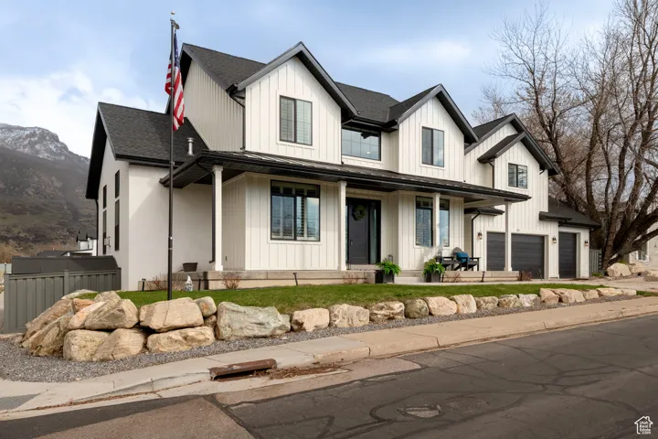 Modern farmhouse style home with board and batten siding, a porch, a garage, and fence