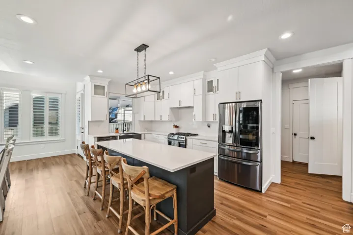 Kitchen with a sink, light countertops, appliances with stainless steel finishes, and light wood finished floors