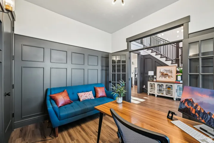 Living area featuring stairs, a towering ceiling, a decorative wall, and wood finished floors