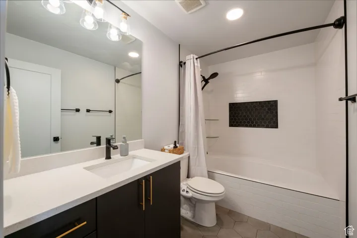 Bathroom featuring toilet, tiled shower / bath combo, vanity, tile patterned flooring, and visible vents