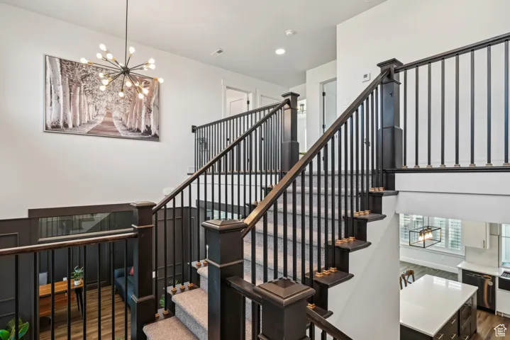 Stairs with wood finished floors, an inviting chandelier, visible vents, and recessed lighting