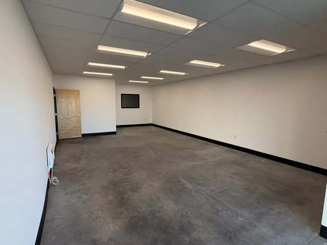 Expansive open-concept room featuring concrete flooring and white walls