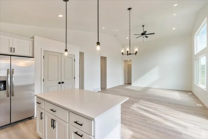 Kitchen featuring a center island, high vaulted ceiling, light wood finished floors, and stainless steel fridge