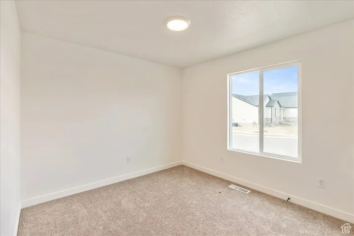 Empty room with light carpet, baseboards, and visible vents