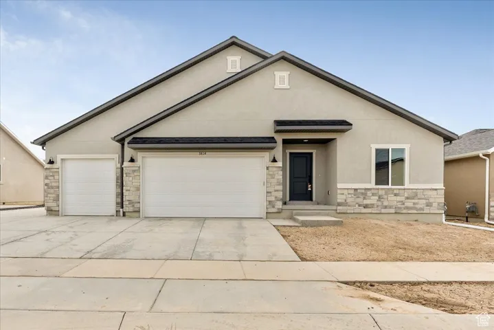 View of front of house featuring concrete driveway, stucco siding, stone siding, and an attached garage