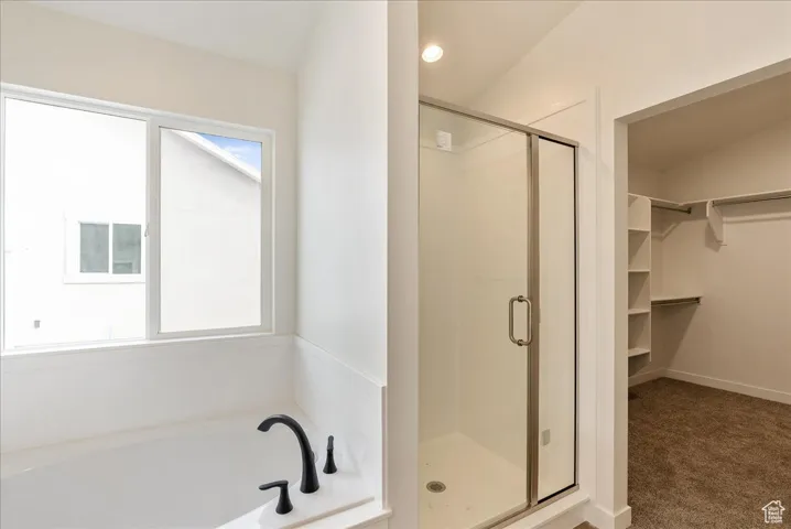 Bathroom with a walk in closet, a stall shower, and a healthy amount of sunlight