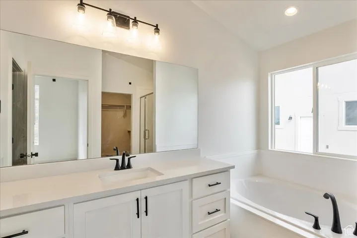 Full bath with recessed lighting, vanity, a garden tub, and lofted ceiling