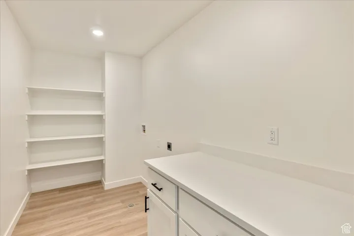 Laundry room with light wood-type flooring, baseboards, hookup for a washing machine, and electric dryer hookup