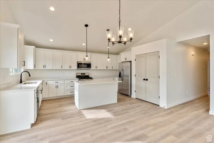 Kitchen with a notable chandelier, light countertops, a kitchen island, appliances with stainless steel finishes, and a sink