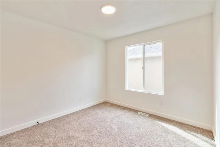 Unfurnished room featuring light colored carpet, baseboards, and visible vents