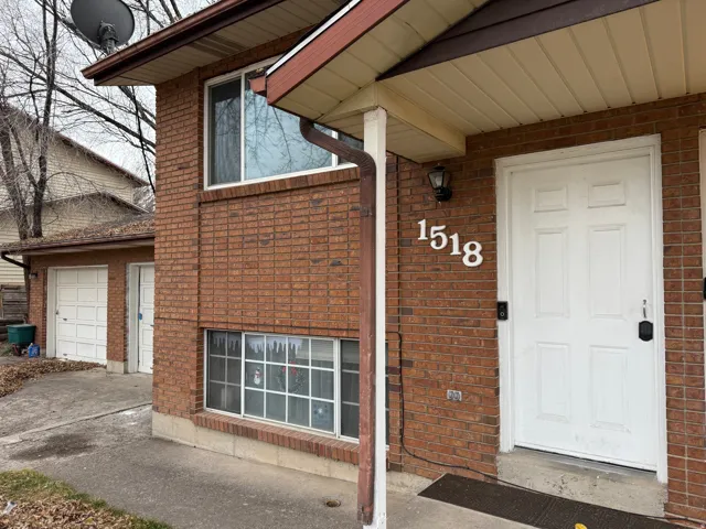 Entrance to property with brick siding, a garage, and covered porch