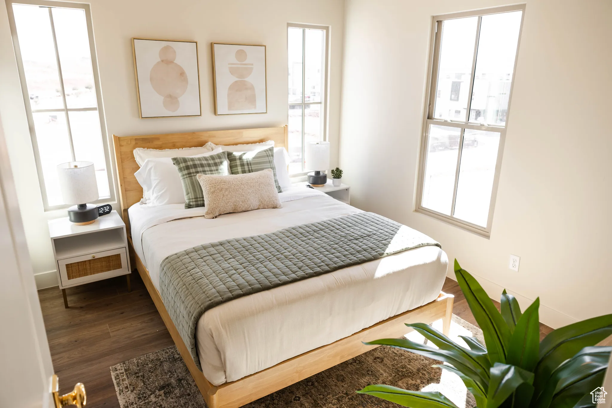 Bedroom featuring multiple windows, baseboards, and wood finished floors