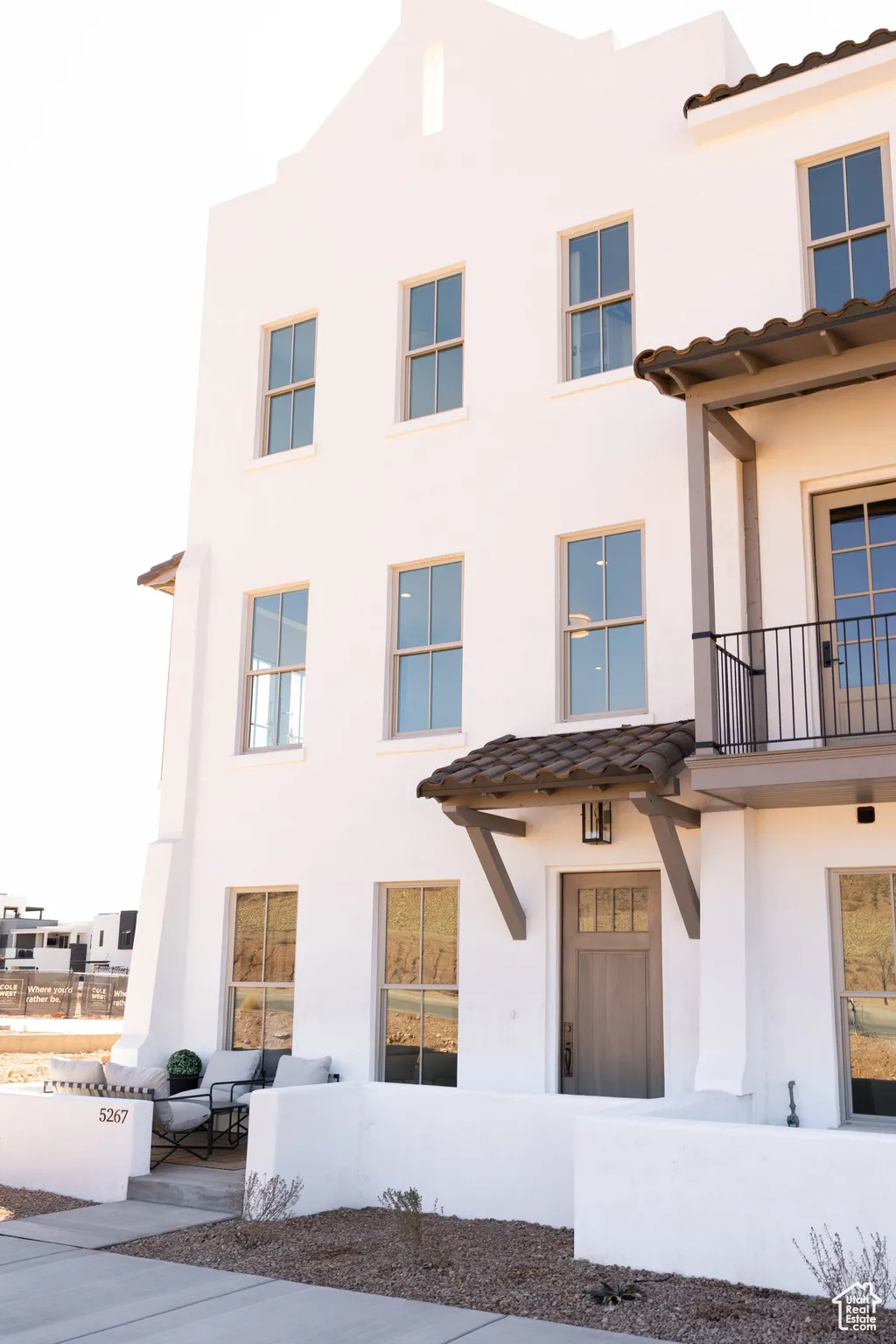 View of front of home featuring a tiled roof, a balcony, and stucco siding