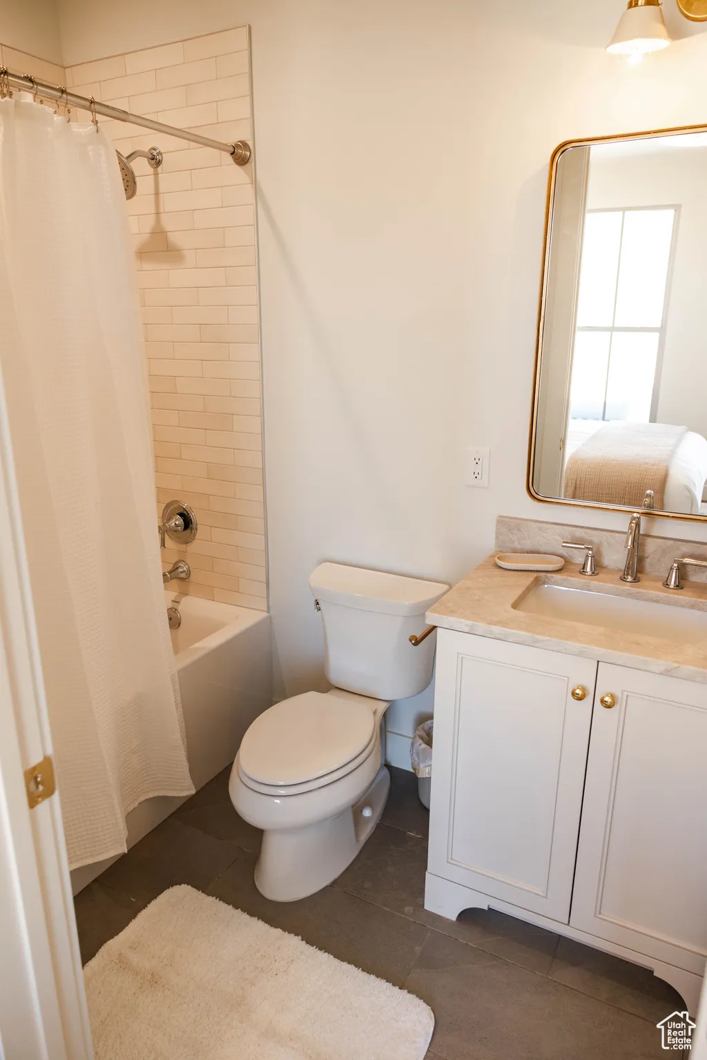 Bathroom featuring tile patterned floors, shower / tub combo with curtain, vanity, and toilet