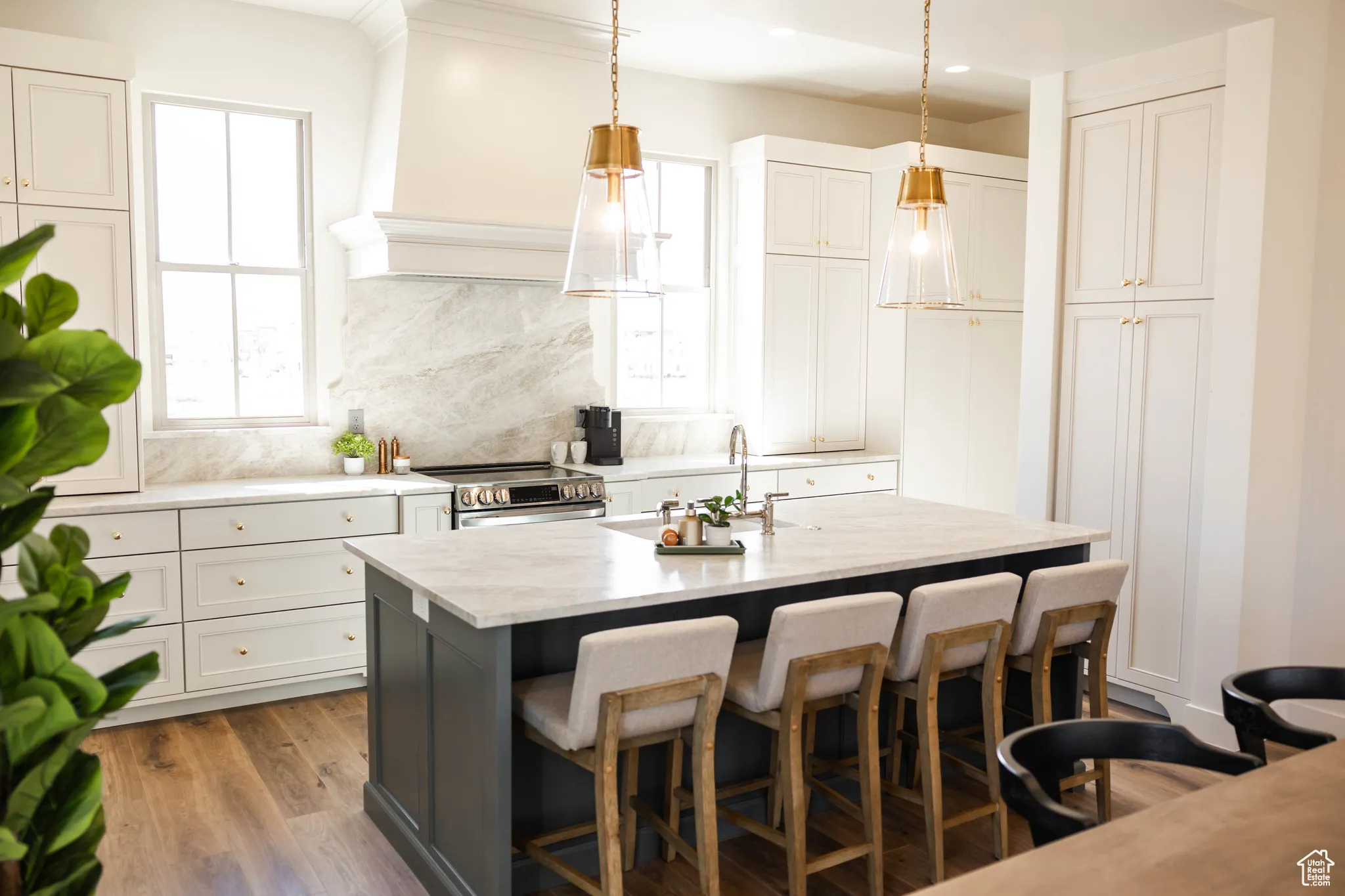 Kitchen with a kitchen breakfast bar, an island with sink, electric range, decorative light fixtures, and wood finished floors