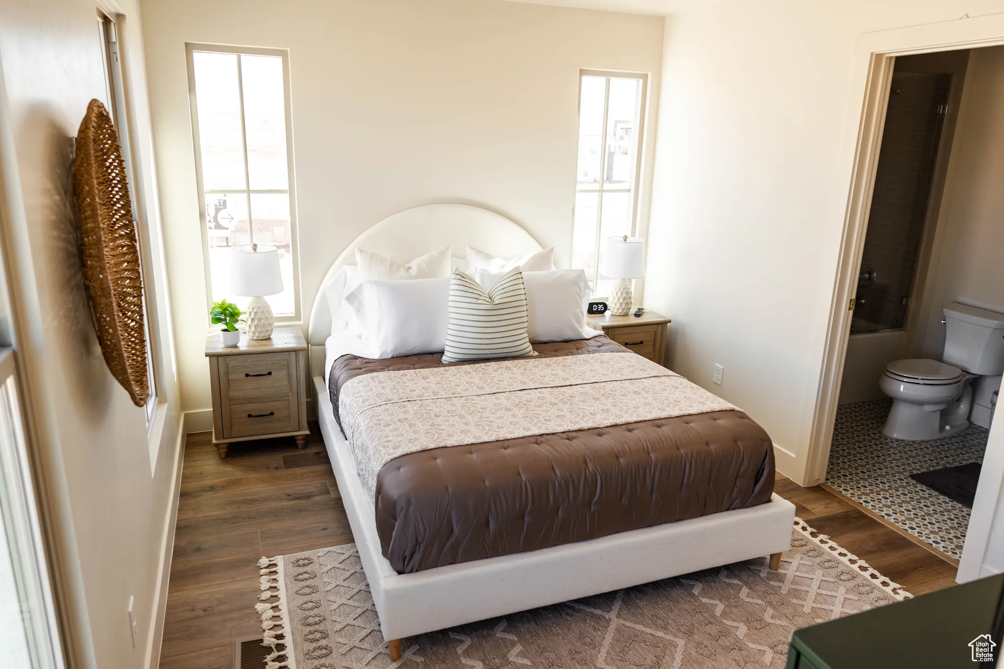 Bedroom with dark wood-type flooring, baseboards, and connected bathroom