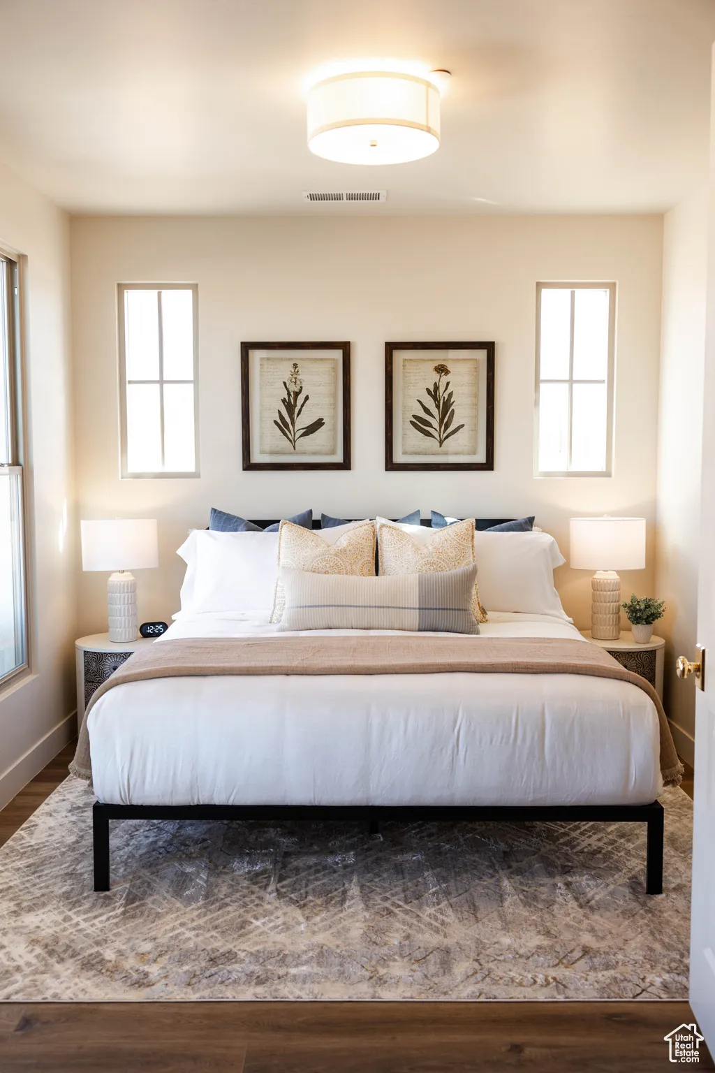 Bedroom with visible vents, multiple windows, baseboards, and wood finished floors