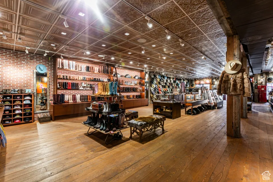 Misc room featuring brick wall, wood-type flooring, and an ornate ceiling
