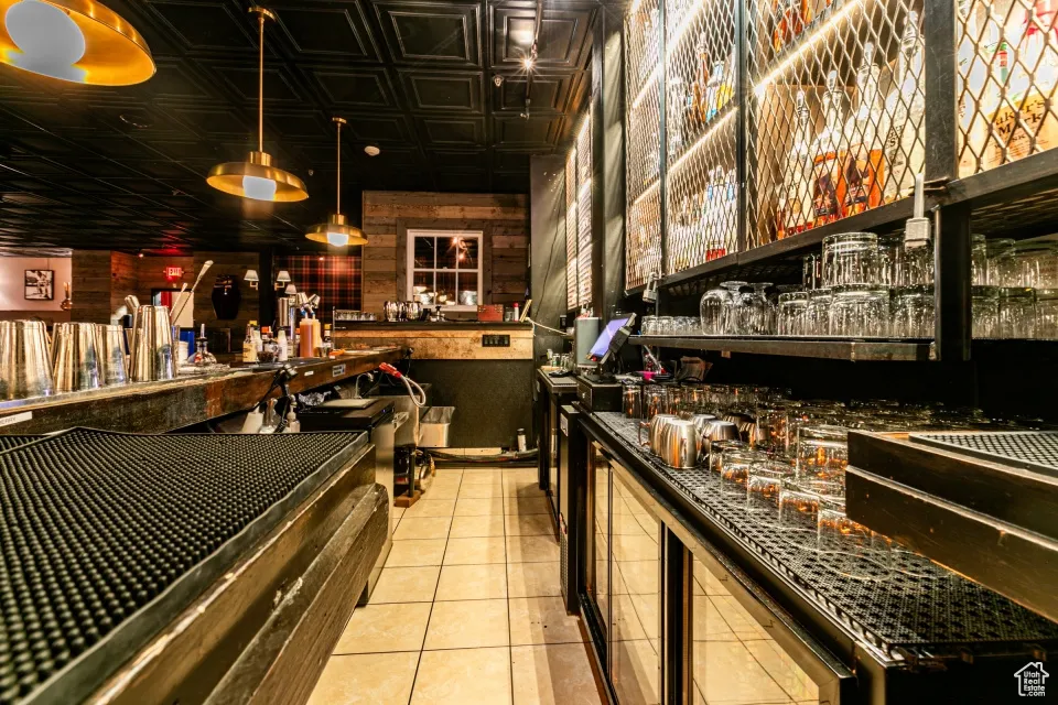 Bar featuring tile patterned flooring, an ornate ceiling, and a community bar