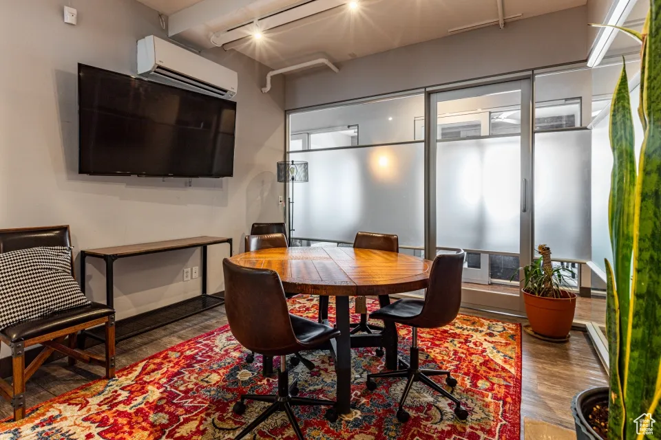 Dining room featuring a wall mounted air conditioner and wood finished floors