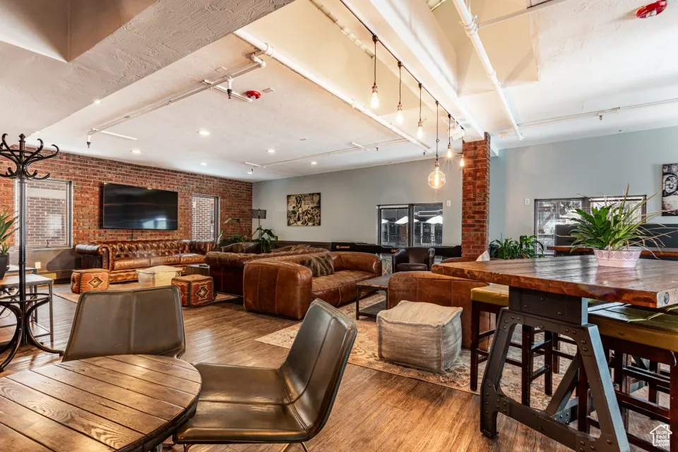 Dining space with brick wall, track lighting, and wood finished floors