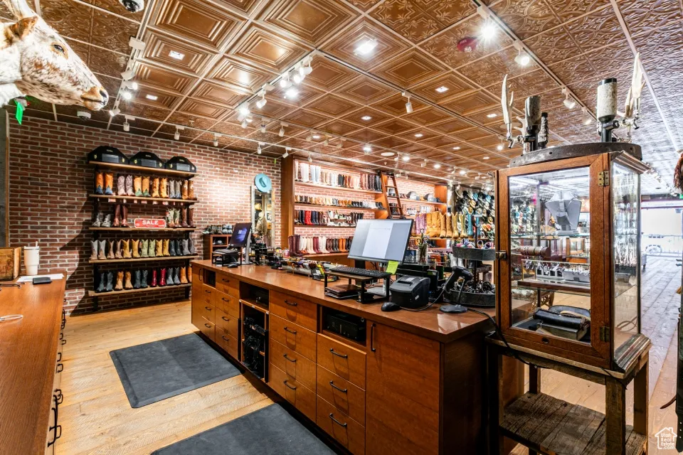 Home office with brick wall, wood finished floors, and an ornate ceiling