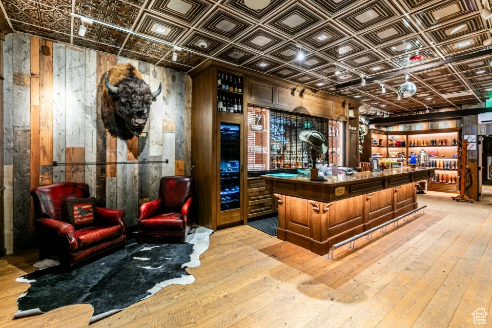 Misc room featuring a bar, wooden walls, an ornate ceiling, and hardwood / wood-style floors