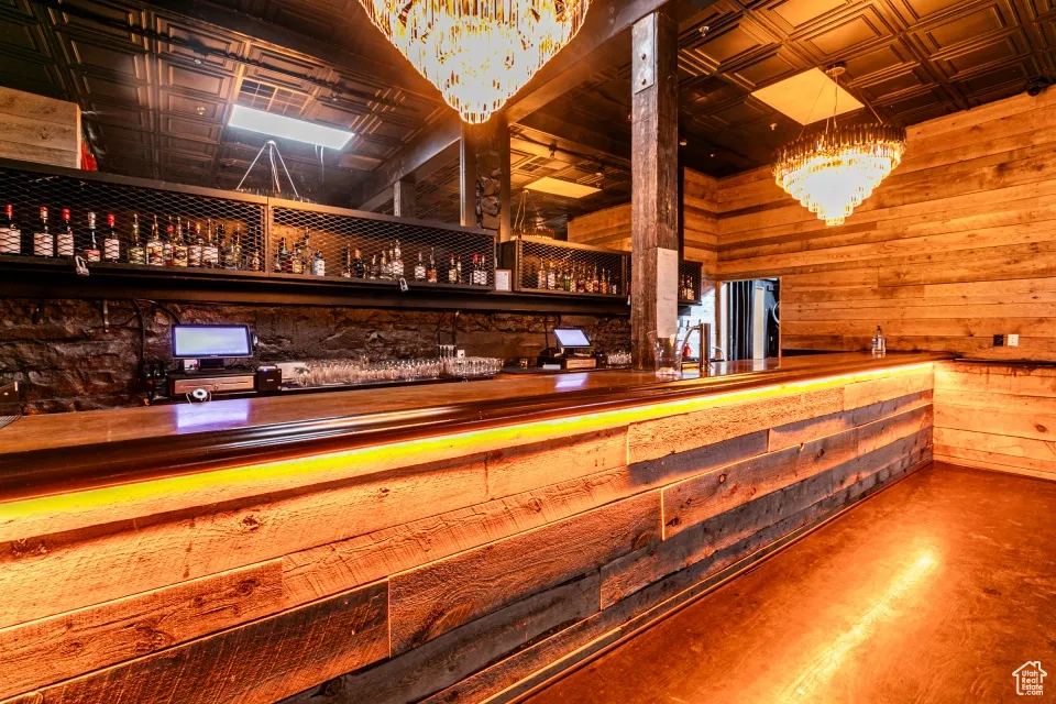 Bar featuring an ornate ceiling, finished concrete floors, a chandelier, and wooden walls