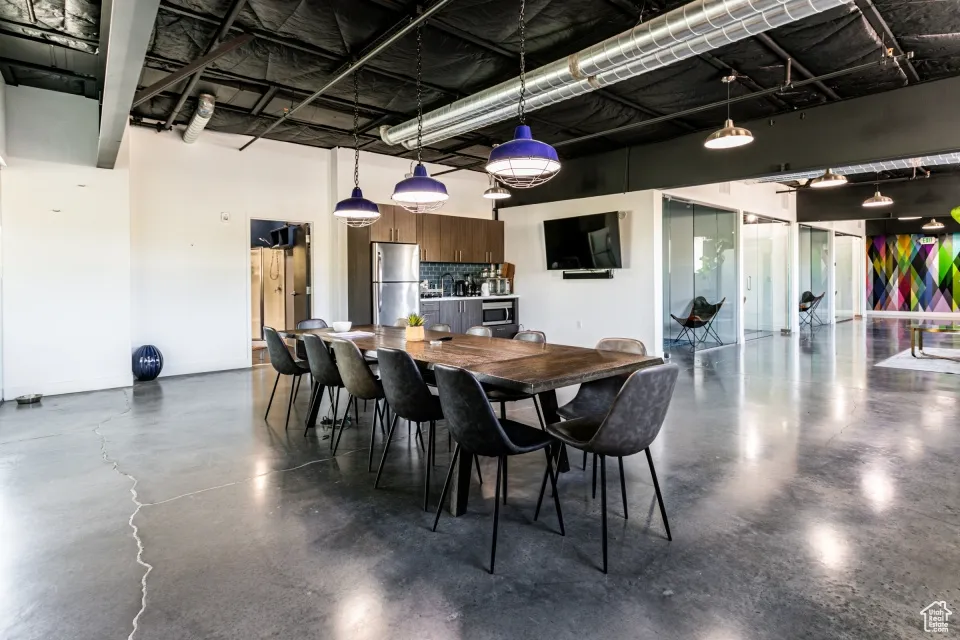Dining area with baseboards, a high ceiling, and finished concrete flooring