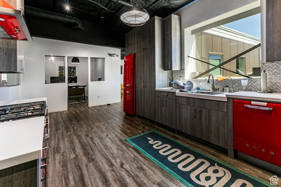 Kitchen with dark wood-type flooring, a sink, decorative backsplash, and light countertops