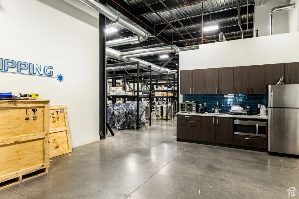 Garage featuring baseboards, a sink, and freestanding refrigerator