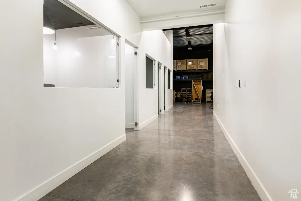 Hallway with finished concrete floors, baseboards, and visible vents