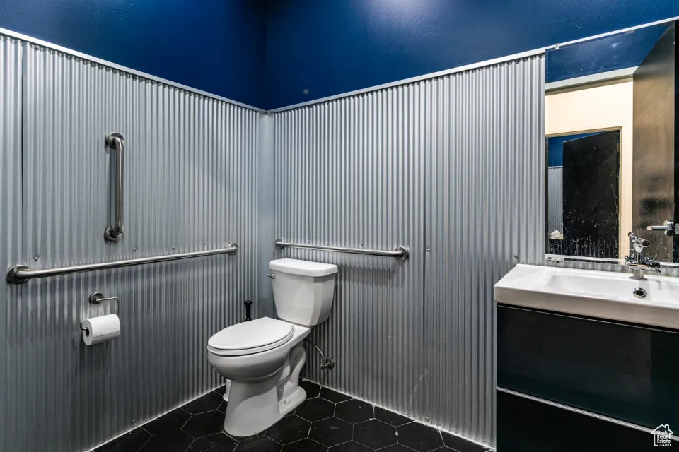 Half bath with toilet, tile patterned floors, and vanity