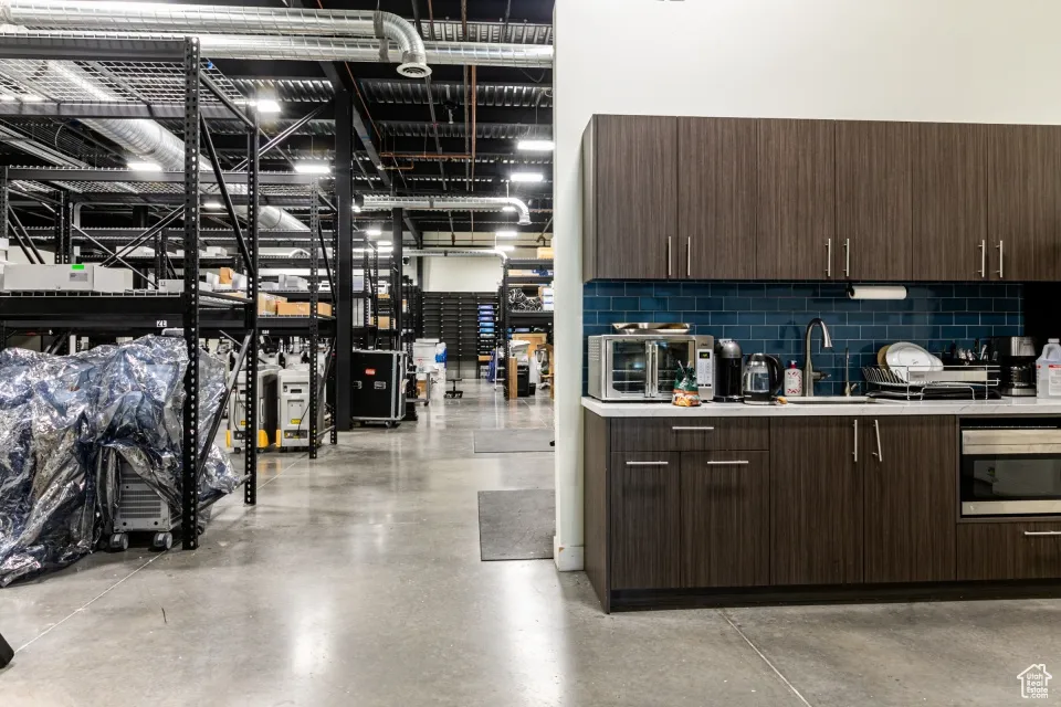 Interior space with dark brown cabinets, backsplash, light countertops, and concrete floors