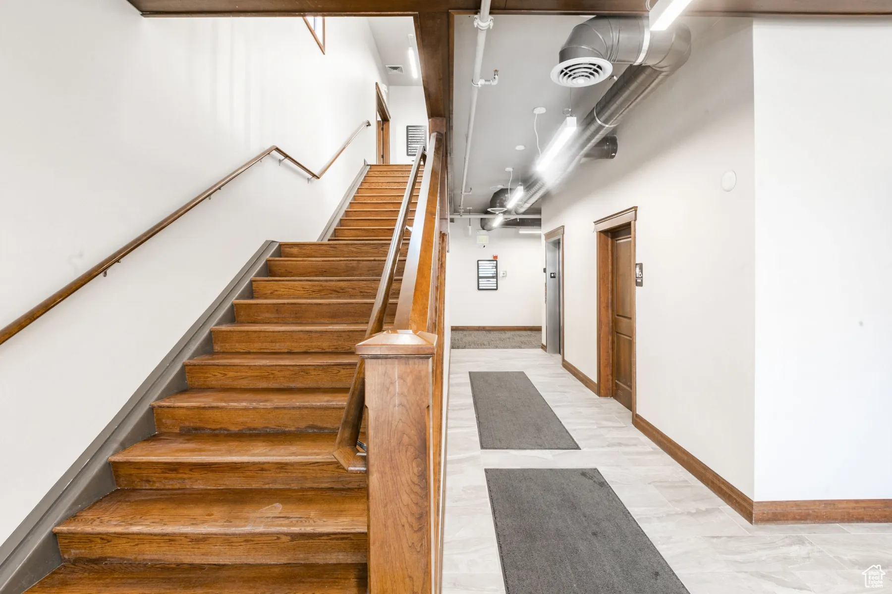 Stairway with wood finished floors, baseboards, and visible vents