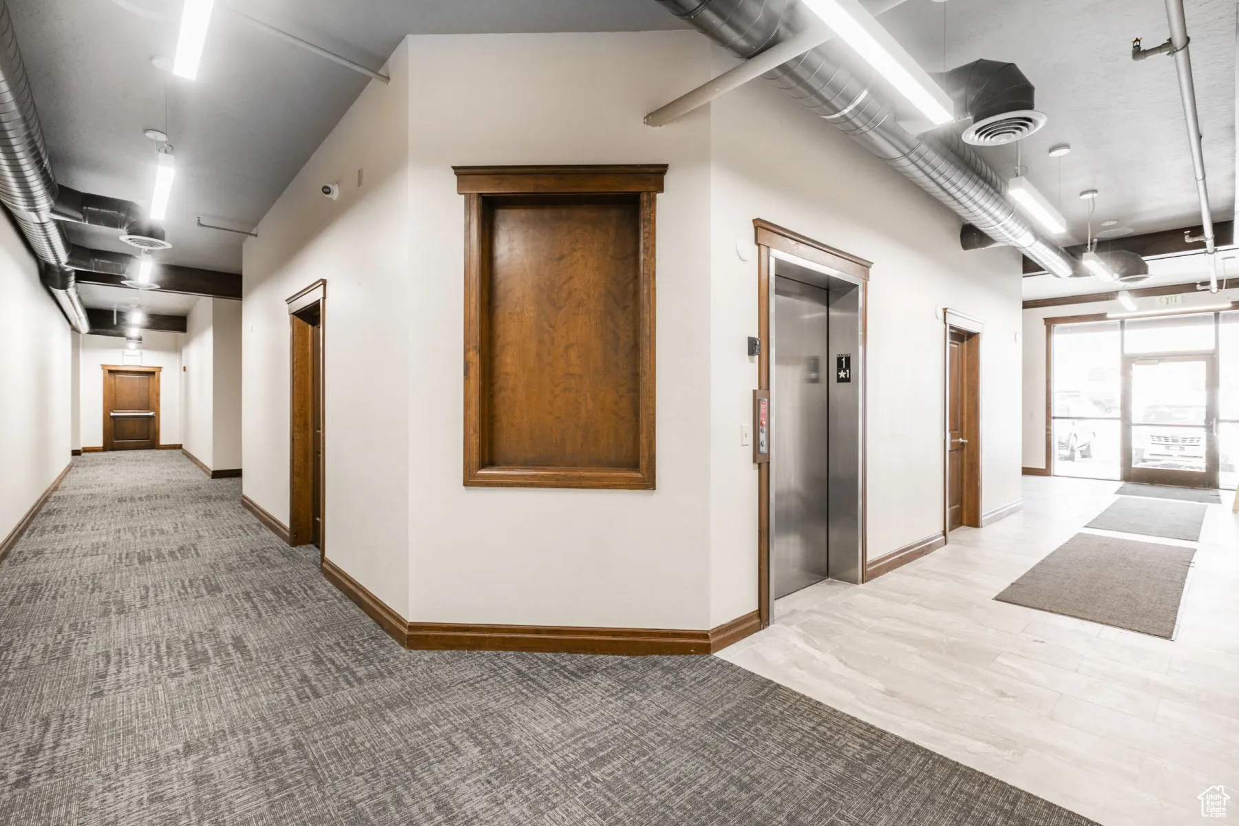 Corridor featuring light carpet, baseboards, visible vents, and elevator